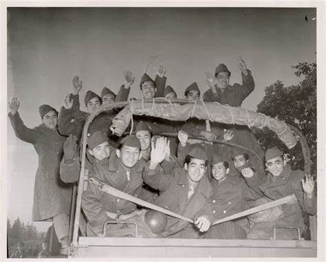 Group of soldiers waving from the back of a truck.