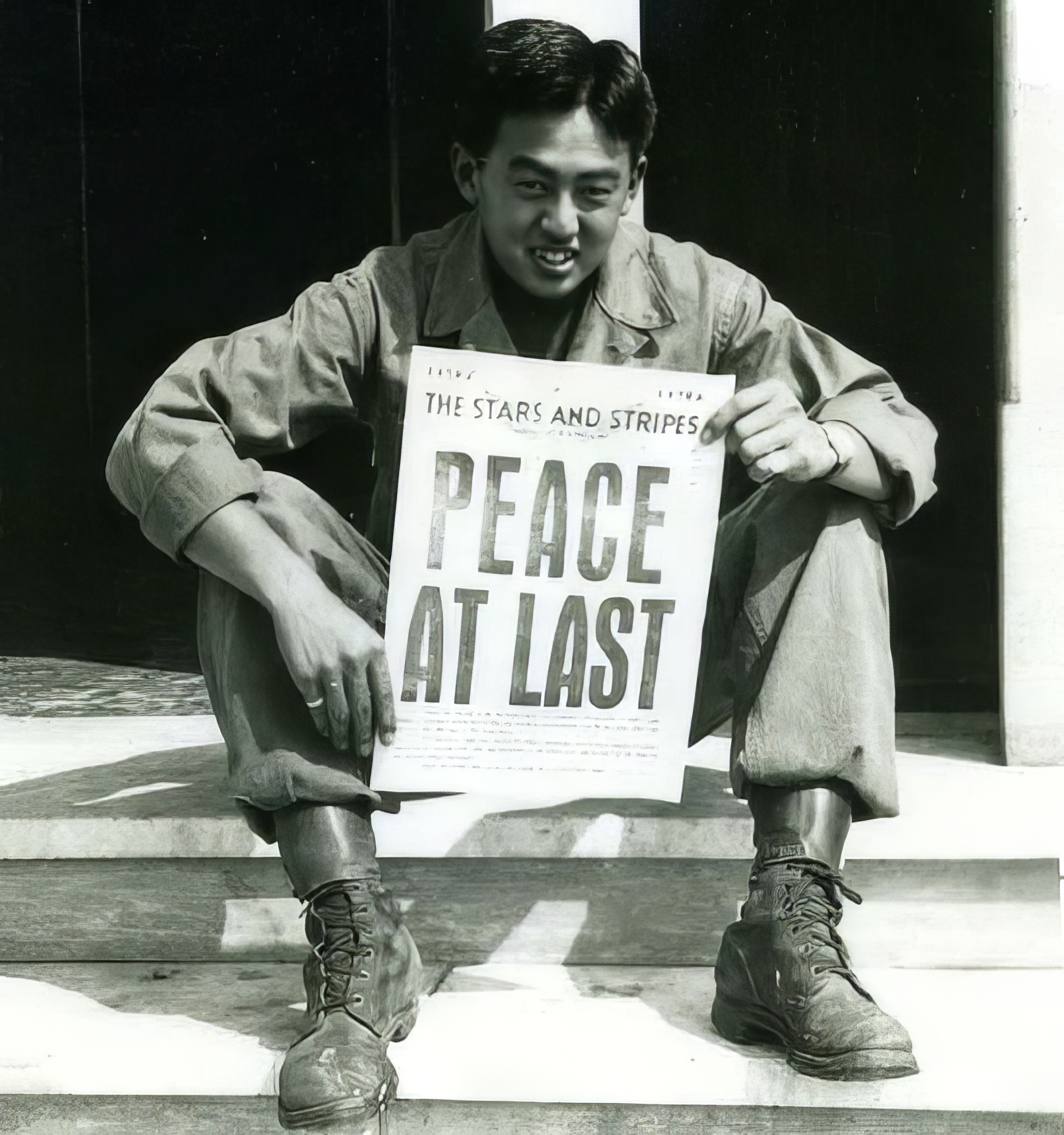 A young 442nd soldier holding a newspaper that reads Peace at Last